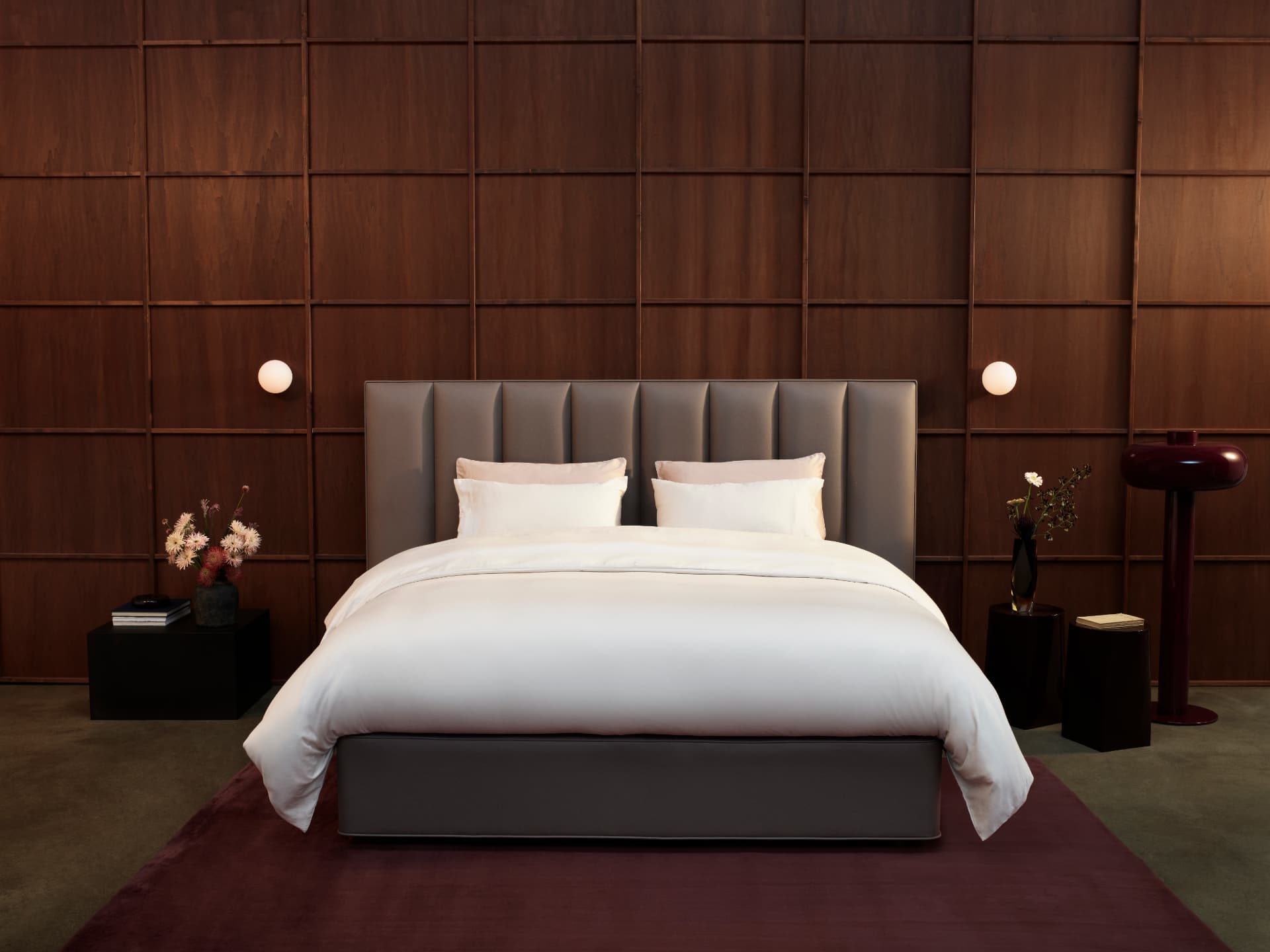 A Luxe Collection bed with a channelled leather headboard against dark timber panelling