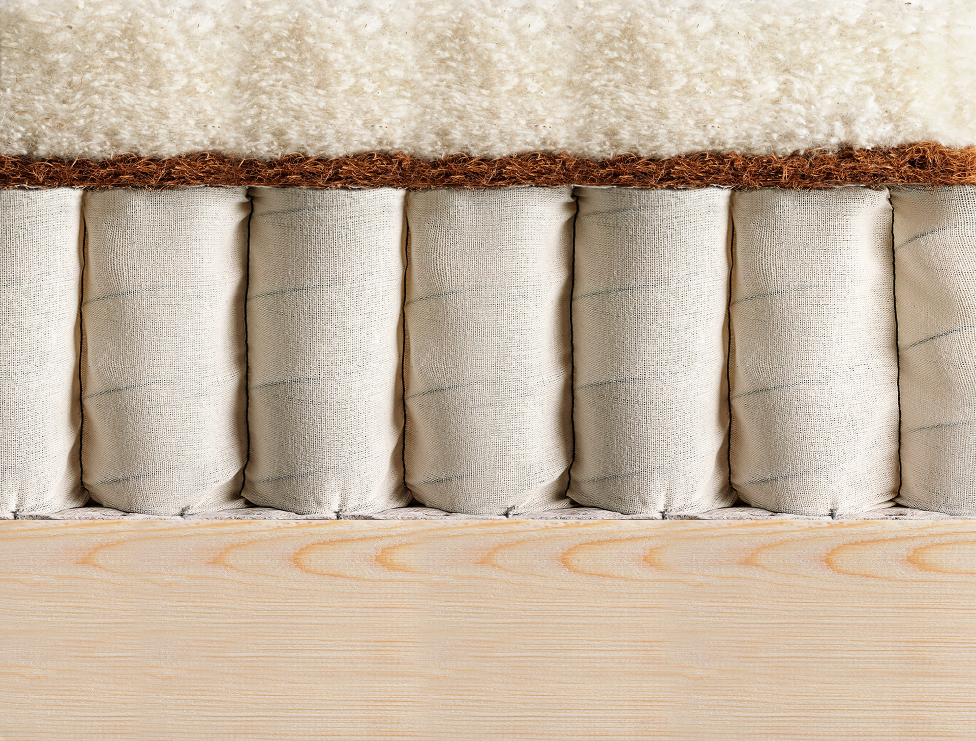 Cut-through of an Original Collection divan base, showing hand-nested pocket springs beneath natural fillings on a timber frame
