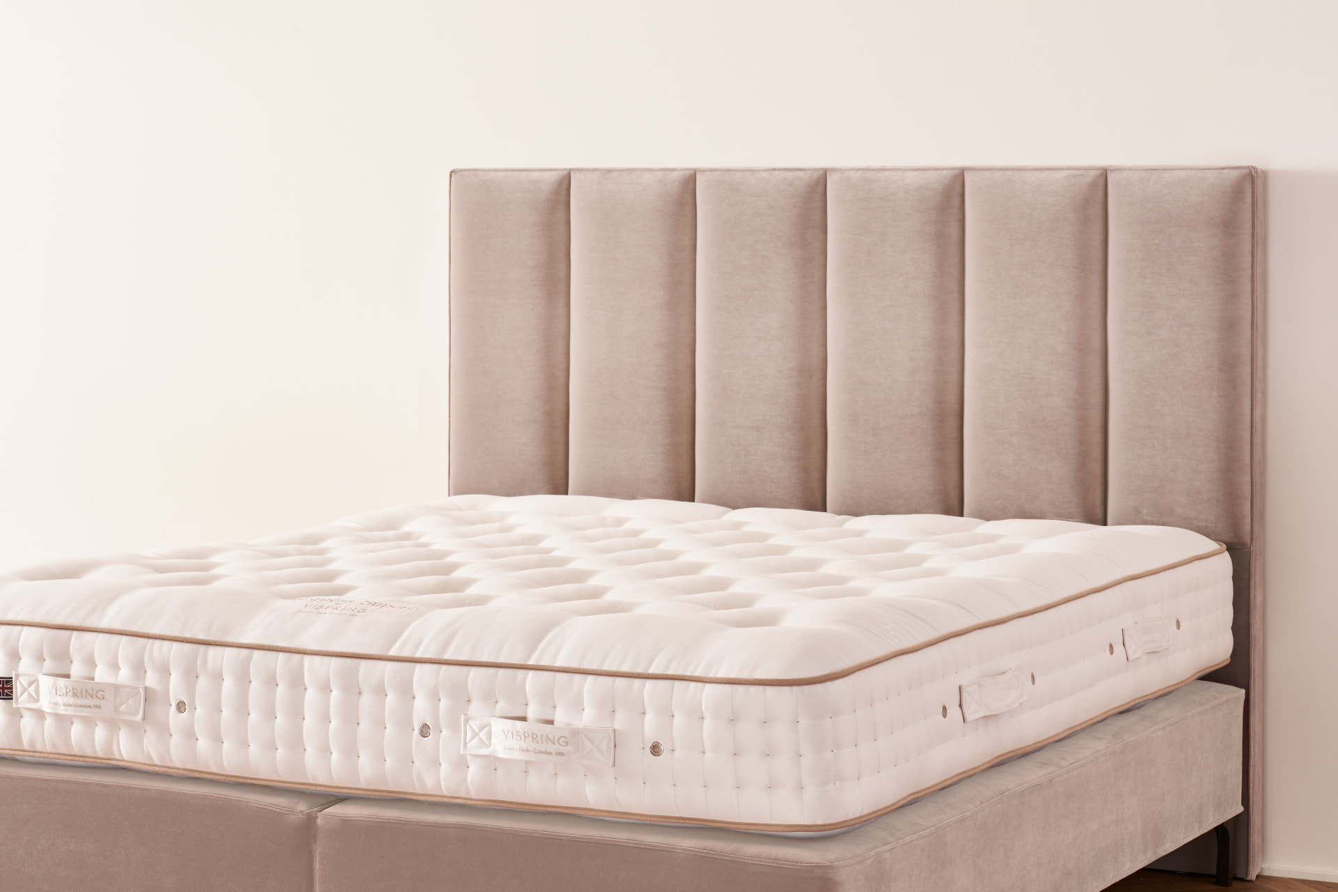 The Ceto headboard, tall vertical channels in a soft taupe fabric on a Vispring bed
