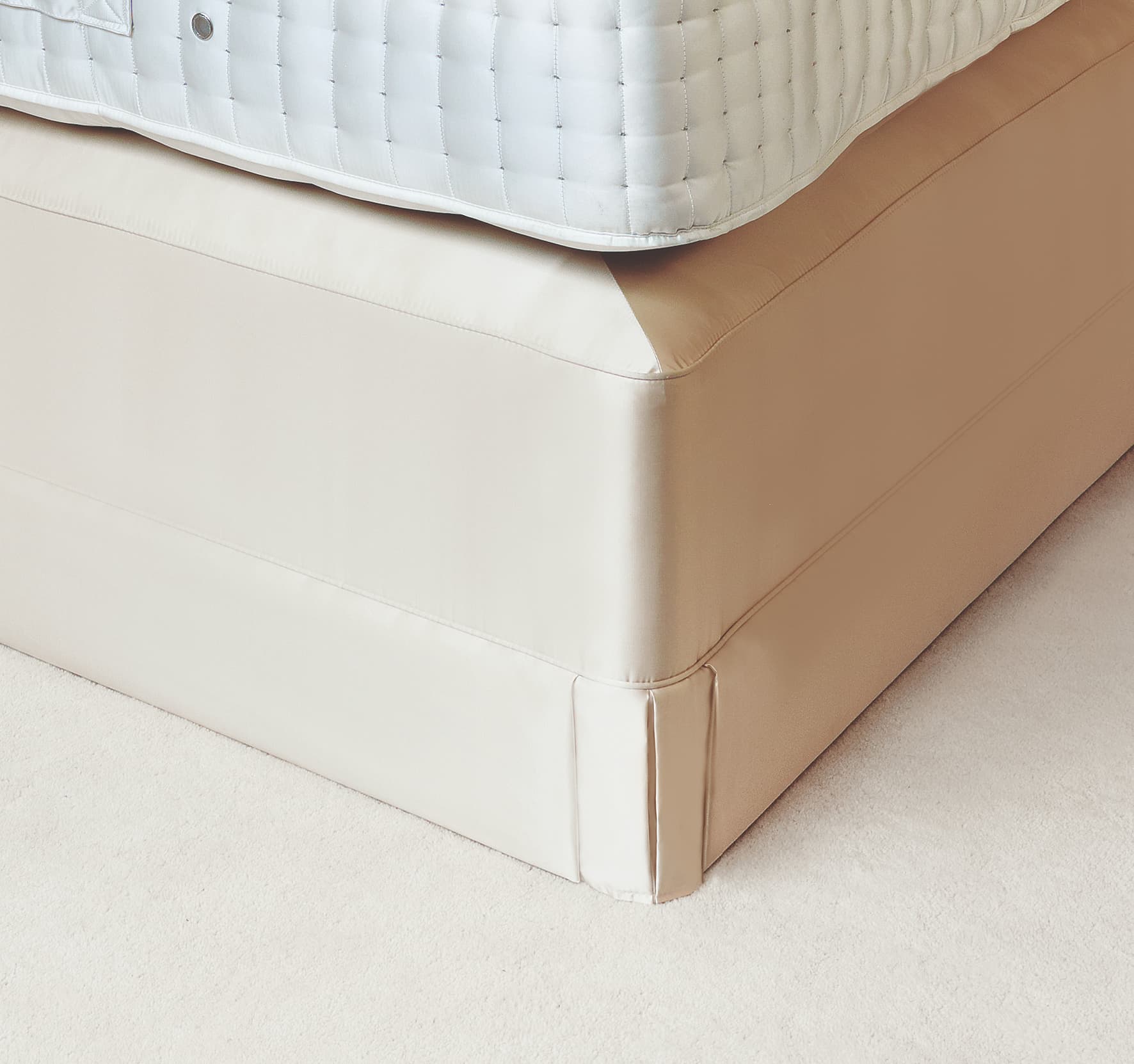 Close detail of a tailored ivory divan skirt wrapping the corner of a divan base