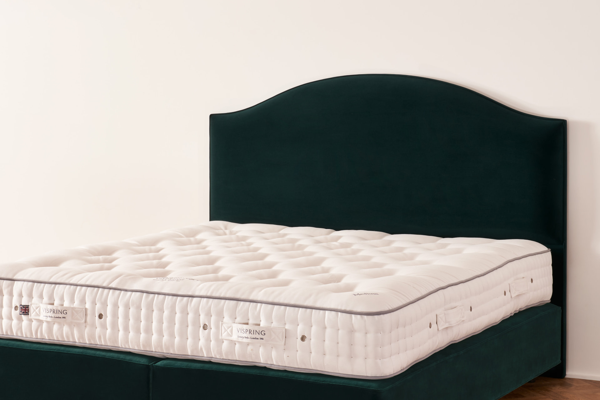 The Clabon headboard, a sweeping curved profile in deep green velvet on a Vispring bed